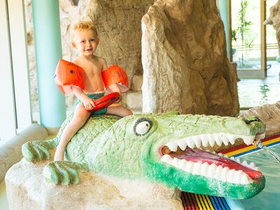 Bub spielt im Erlebnisbad auf Krokodil