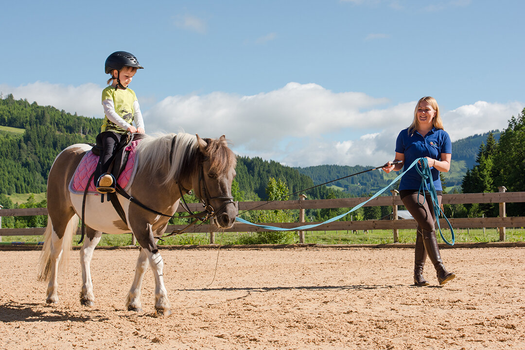 Mädchen mit Reitlehrerin auf Reitplatz