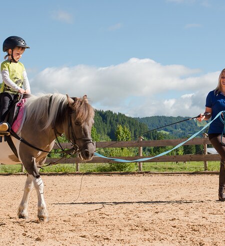 Mädchen mit Reitlehrerin auf Reitplatz