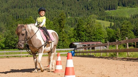 Kleines Mädchen beim Reiten am Reitplatz