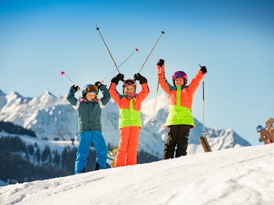 Kinder im Skikurs halten die Stöcke hoch